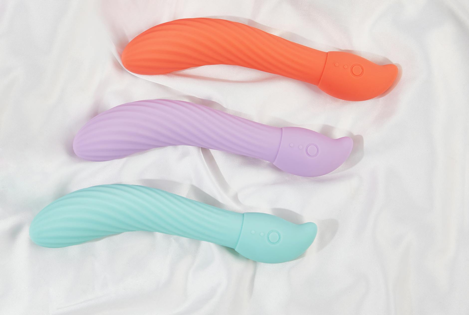 Frau hält rosafarbene und blaue Silikonvibratoren in den Händen und erkundet neue Möglichkeiten der Intimität