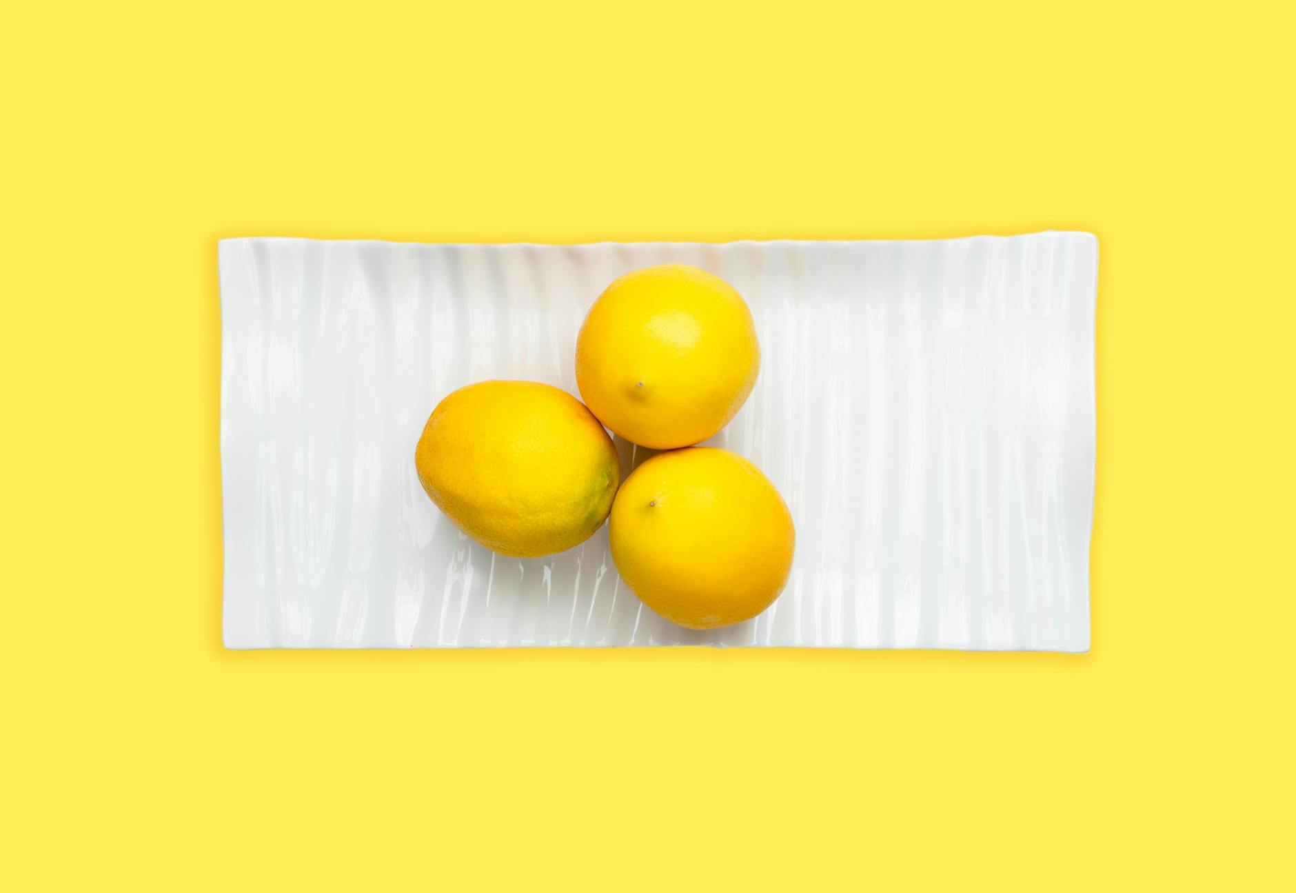 Fresh lemons arranged on white plate with yellow background, symbolizing reconnection and renewal