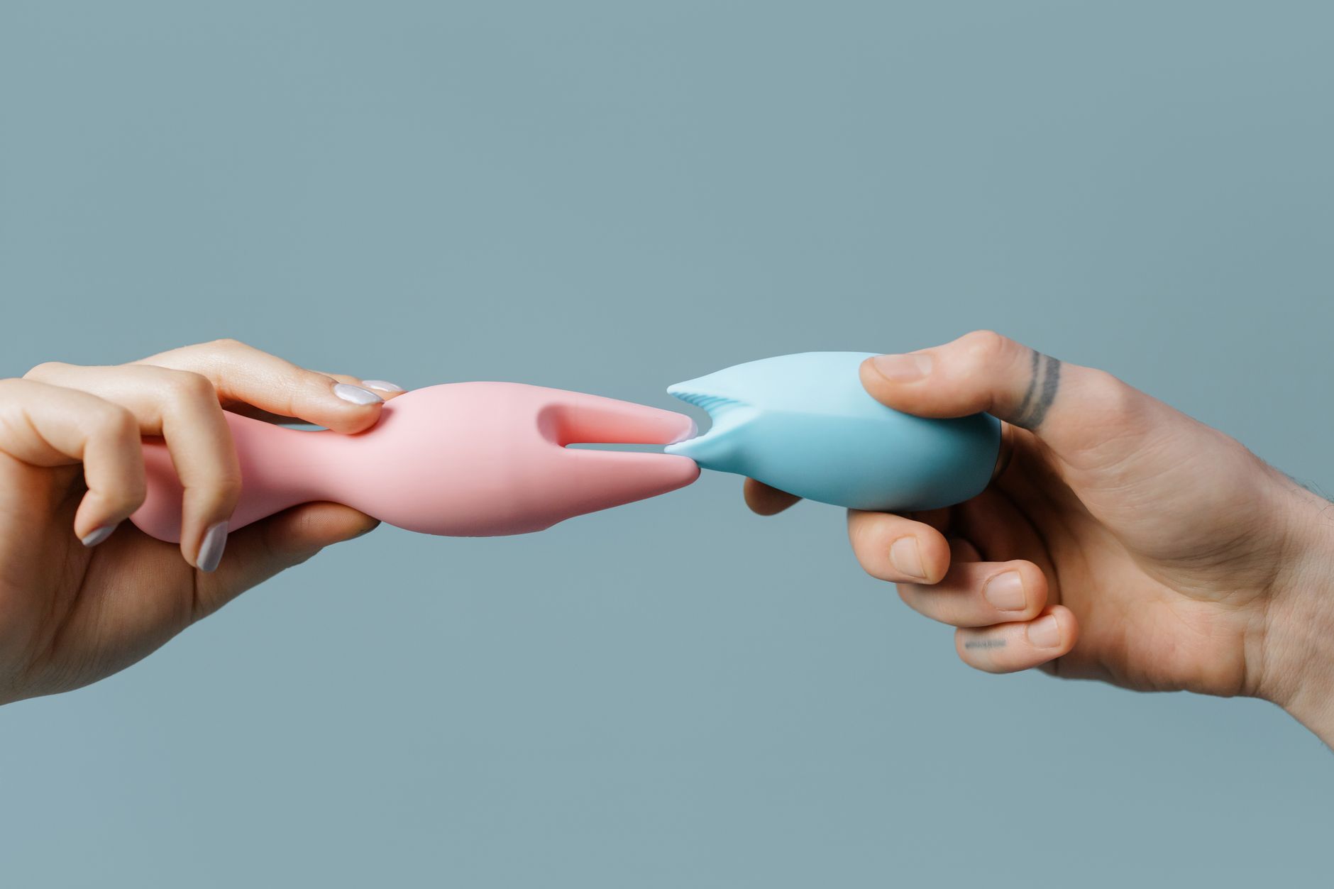 Eine Person hält einen pastellfarbenen Vibrator in ihren Händen gegen einen ruhigen Hintergrund