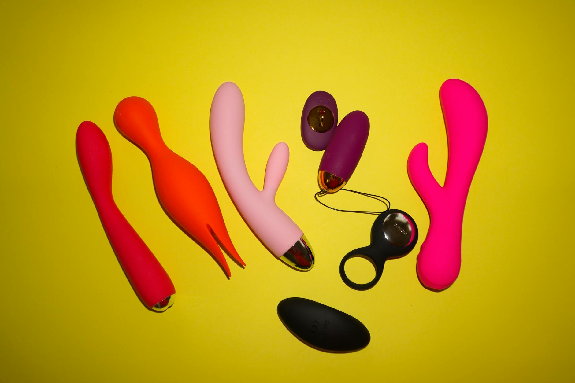 Colorful vibrators and intimate wellness toys arranged on a bright yellow background